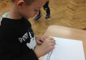 CHłopiec rysuję weglem